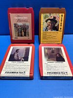 Four 8-track tapes placed side by side, showing front labels of each tape with artist names and track listings.
