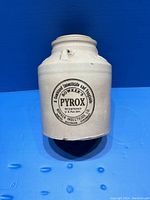 Front view of the antique stoneware jar showing black printed circular label and inscription of Bowker's Pyrox insecticide marking.