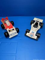 Front and side view of red and white FP Toys firetruck and white racecar on blue background