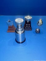 Four miniature NHL trophies arranged on blue background showing all details