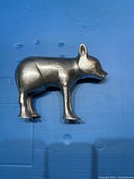 Side profile of a pewter bear figurine showing smooth silver-gray metal and bear shape.