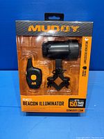 Front view of the Muddy Remote Beacon Illuminator sealed in original packaging, showing remote control and beacon with mounting bracket.