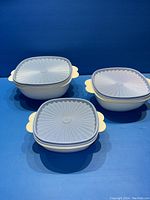Photo showing three Tupperware containers arranged with lids on, emphasizing design and color.