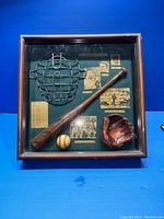 Clear front view of the shadow box showing all contents mounted against a dark green fabric background.