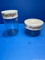 Both Pyrex canisters next to each other showing their size difference and Spice of Life patterned lids.