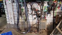 Wide shot of multiple chains and hoses hung on wall with chains coiled on floor beneath