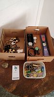 Full lot overview with all watches, costume jewelry, pins and earrings in boxes and containers