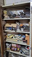 Full view of four metal shelves filled with grinder parts and accessories including discs, pads, belts, and small tools.