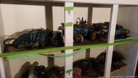 Shelved lot with five electric grinders including Bosch and Ryobi models, cords wrapped, dusty and lightly used appearance.
