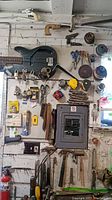 Wide view of hand tools mounted on a wall including saws, tape measures, locks, scissors, pliers, and miscellaneous hand tools.