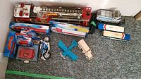 Wide shot showing all model vehicles including red fire engine, wooden models, boxed Canada Post trucks, and Greyhound buses.