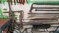 Image of wall-mounted assortment of pry bars and greaser tools including flat, hooked, angled pry bars and several greaser tools showing signs of heavy use.