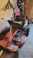Front view of red ride on mower with black seat and steering handles.