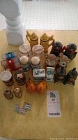 Overview photo showing group of vintage salt and pepper shakers with various materials and designs, arranged on brown surface
