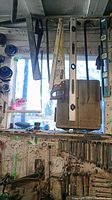 Tools hanging on a wooden wall, showing wrenches, sockets, hand saw, spirit levels, crowbar, and metal rods.