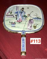 Full front view of porcelain hand mirror showing painted scene and handle