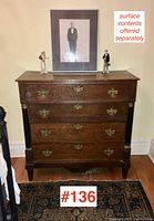 Front view of the antique English oak chest showing four drawers and brass hardware, with decorative surface items noted but sold separately.