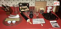 Wide photo showing assorted kitchenware items including knife block, glassware, rolling pin, sushi mat, cutting boards, timer, and more on a red countertop.