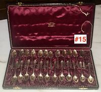 Open presentation case showing all 24 coffee spoons arranged in burgundy velvet interior