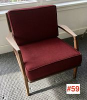 Front three-quarter view showing the teak frame, angled armrests and red seat/back cushions.