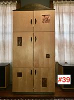 Front view of tall entertainment armoire showing birch wood doors with black stained handles and base, featuring five copper embossed panels in door cut-outs.