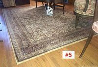 Carpet corner showing inner field and outer border against hardwood floor