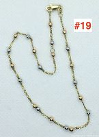 Full view of the 9-inch anklet showing alternating yellow and white gold beads on a twisted chain with lobster clasp.