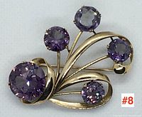 Front view showing overall design with five purple amethyst stones and gold swirl setting