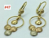 Pair of 14k tri-colour gold earrings showing front view with three textured spheres and a dangling smooth sphere in the hoop.