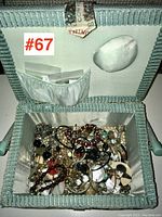 Open fabric-covered jewellery box showing assorted mixed costume and fine jewellery tangled inside.