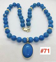 Full view of necklace laid flat showing turquoise beads, gold spacers and pendant