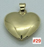 Front view of a polished gold heart-shaped pendant showing smooth reflective surface and 10k gold bail.