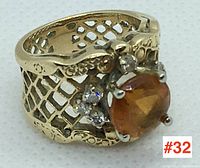 Three-quarter front view of ring on white background showing lattice band, citrine center and diamond cluster.