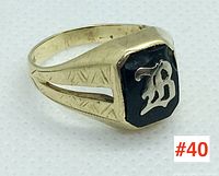 Angled side view of a 10k yellow gold signet ring with a black enamel face and silver 'B' initial, showing side engravings on the band.