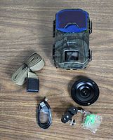 Apeman H55 trail camera and included accessories laid out on a wooden surface.
