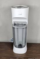 Honeywell Cool Moisture Tower Humidifier in white with transparent front water tank, placed on a wooden surface.