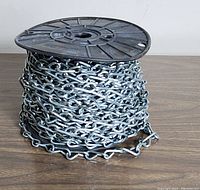 Full view of a plastic spool wound with silver-plated metal jack chain, showing chain links and spool details.