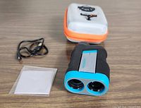 Mileseey PF260 laser rangefinder, USB charging cable, cleaning cloth, and carry case on a flat surface.