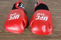 Top view of the red UFC Gym boxing gloves showing the front with logo and padded knuckle area.