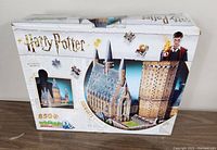 Front of box showing 850+ piece Wrebbit 3D puzzle of Harry Potter Hogwarts Great Hall with distressed packaging.