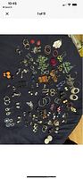 Photo showing a large assortment of earrings laid out on dark fabric, featuring multiple styles, colors, and materials.