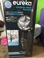 Box front showing product name, key features like 2-in-1 cordless design, 60-minute lithium battery runtime, foldable handle, and LED headlights.