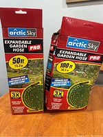 Photo showing two unopened boxes of Arctic Sky Expandable Garden Hoses Pro, 50 ft and 100 ft lengths.