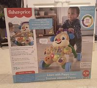 Front packaging image showing Fisher-Price Learn with Puppy walker for ages 6 to 36 months with interactive features.