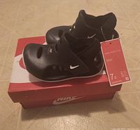 New black Nike toddler sandals placed on top of Nike box with size 7C tag attached.