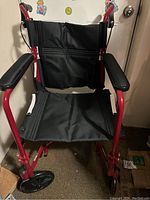 Full front view of transport wheelchair showing frame, seat, backrest and wheels