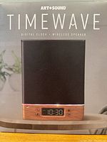 Box front image showing Art+Sound Timewave wireless speaker with digital clock on wooden base and black speaker cover.