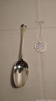 Top side view of the sterling silver tablespoon with tag indicating 'Tablespoon Newcastle Ca. 1755'.