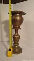 Full view of brass pedestal planter with measuring tape showing height around 19 inches.
