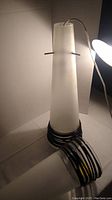 Conical frosted glass light fixture with black banding resting upright with power cord visible